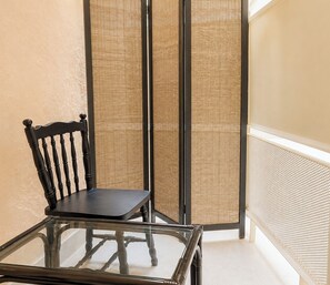 A glass-top table with a black chair, a woven partition, and a white wall. - Modern Basement Studio - Kolonaki by ΜΡS (Athina)