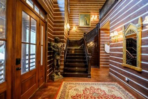 A wooden interior with a staircase, a statue, and a patterned rug. - Wizard Cabin+Treehouse | Game Zone | Sleeps 23 (Broken Bow)