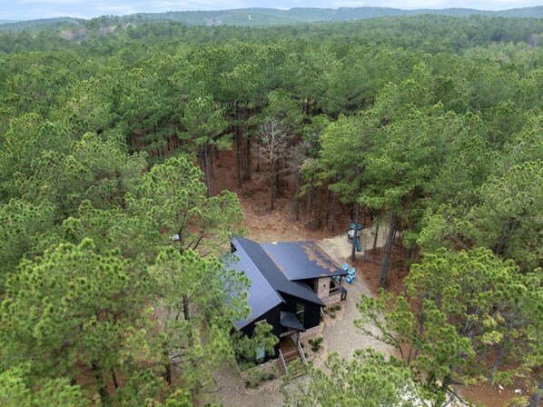 Eine Hütte, umgeben von dichtem Wald, mit einem Kiesweg, der dorthin führt.