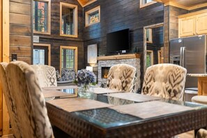 A wooden interior with a fireplace, a television, and a dining area with chairs and a table. - 2 King Suites | Hot Tub+Game Room | Sleeps 8 (Broken Bow)