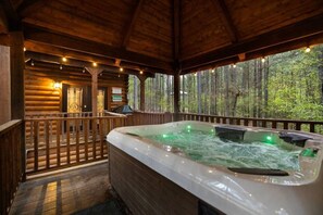 A wooden cabin with a hot tub, wooden deck, and a forest view. - 2 King Suites | Hot Tub+Game Room | Sleeps 8 (Broken Bow)