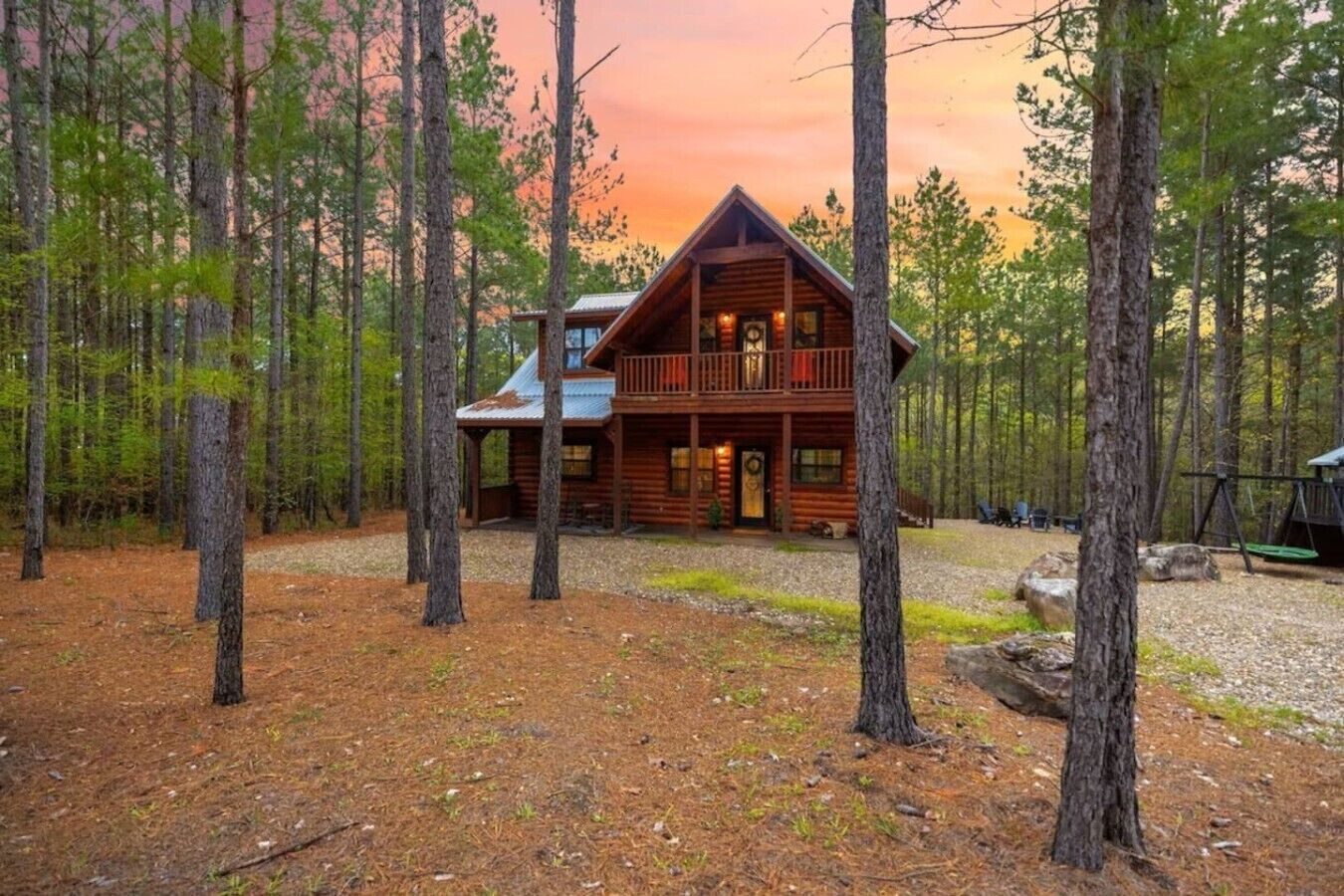 Una cabaña de troncos con balcón, rodeada de un bosque.