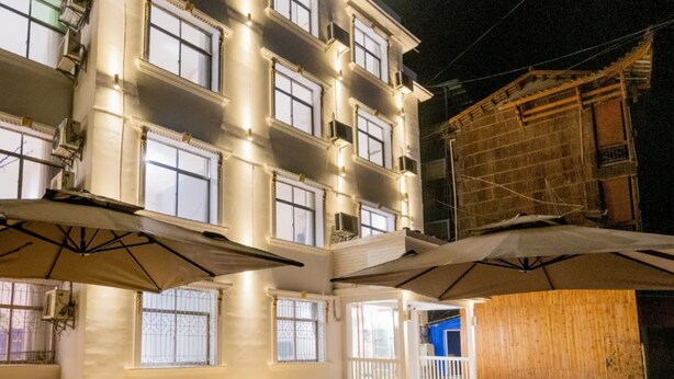 Um edifício com vários andares, varandas, janelas amplas e uma área externa coberta.