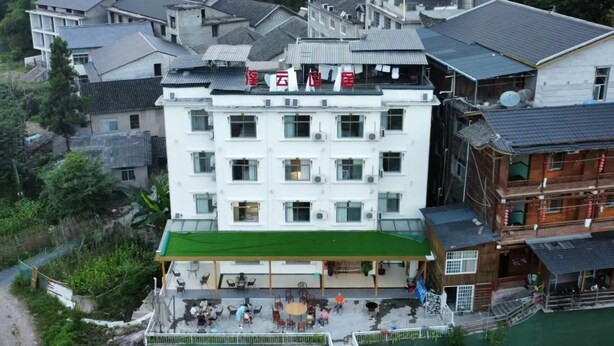 Un hotel a più piani con un'area esterna ricoperta di verde, circondato da edifici tradizionali.