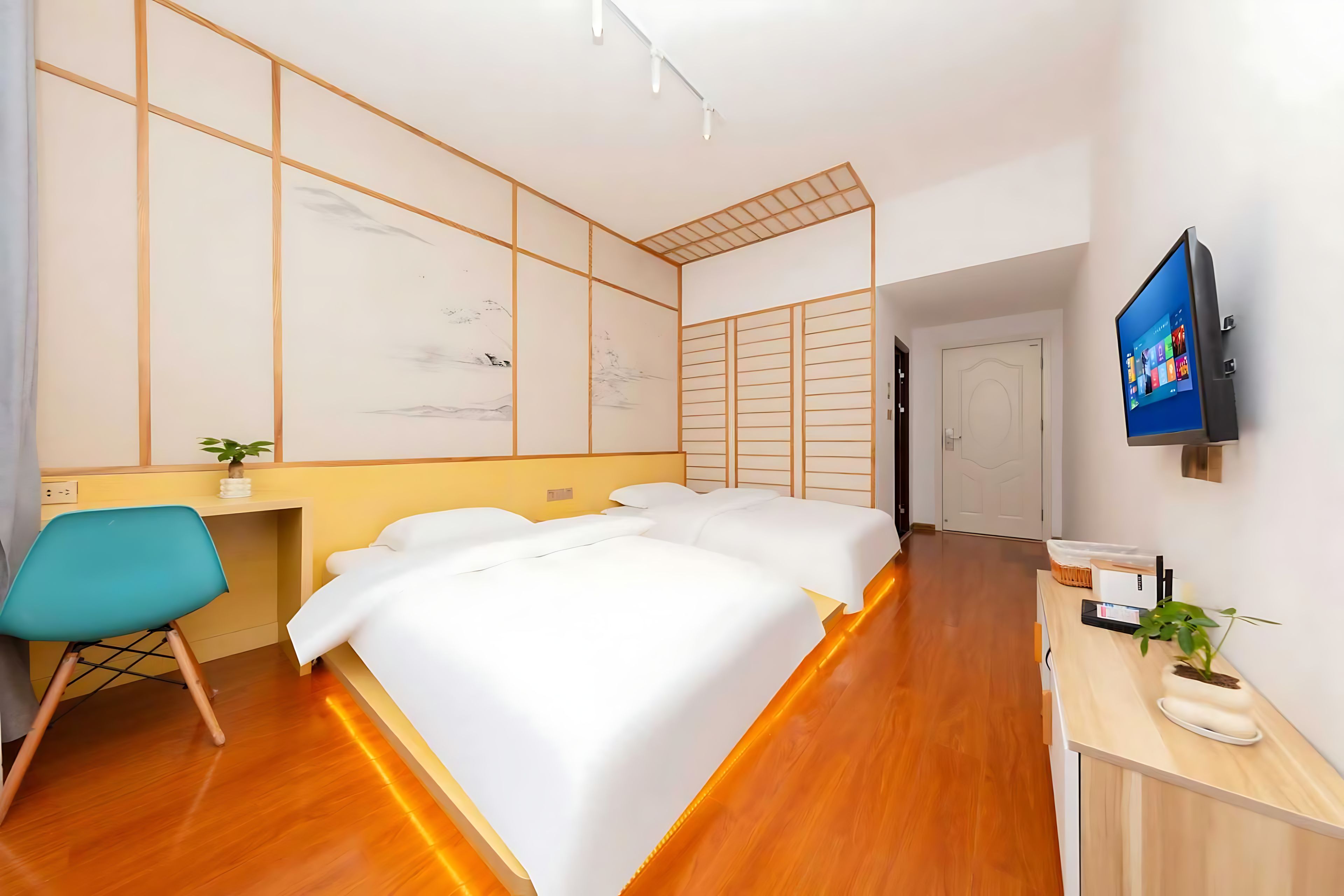 Habitación de hotel con cama, escritorio, silla, televisor y planta.