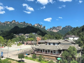 A traditional building with a tiled roof, surrounded by lush greenery and mountains in the background. - Xiyoon Yangjiajie Mountain Inn (Zhangjiajie)