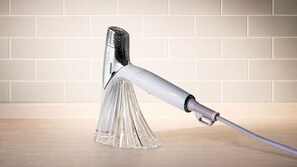 Ein klares Objekt mit Henkel und strukturierter Oberfläche, platziert auf einer ebenen Fläche vor einer gefliesten Wand.