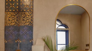 A bathroom with a decorative shower wall, a sink with a mirror, and a potted plant. - Staymaster Cove Villa (Parra)