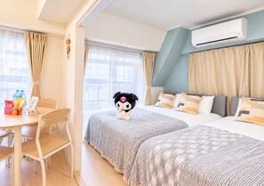 Ein Hotelzimmer mit zwei Betten, einem Schreibtisch mit Stuhl und einer Klimaanlage.