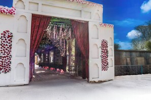 Una estructura blanca con un umbral abierto, decorado con cortinas rojas y motivos florales.