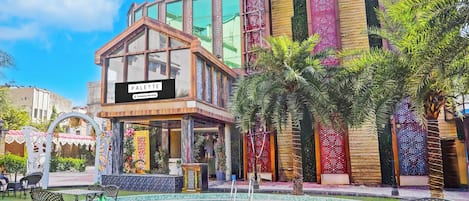 A modern building with a sign reading 'PALETTE' and a pool area with lounge chairs and a fountain.