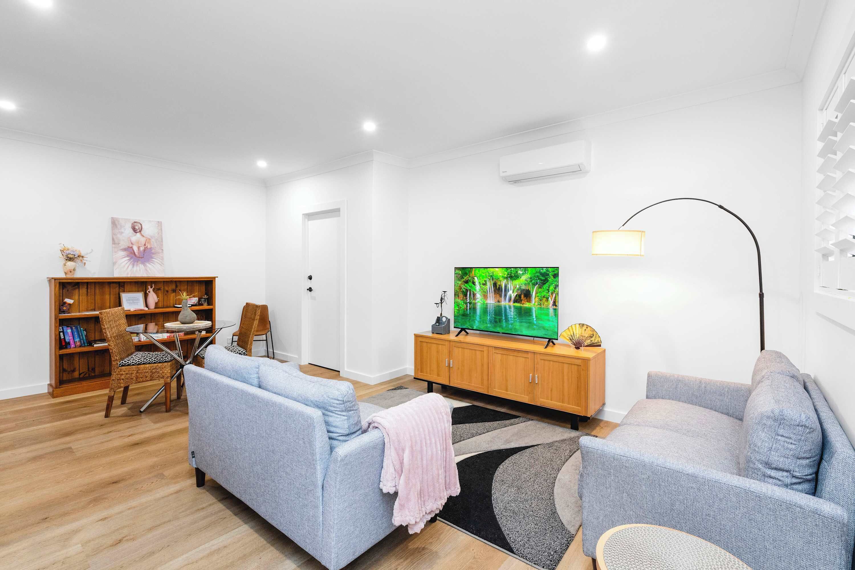 A modern living room with a sofa, TV, wooden cabinet, and a bookshelf.