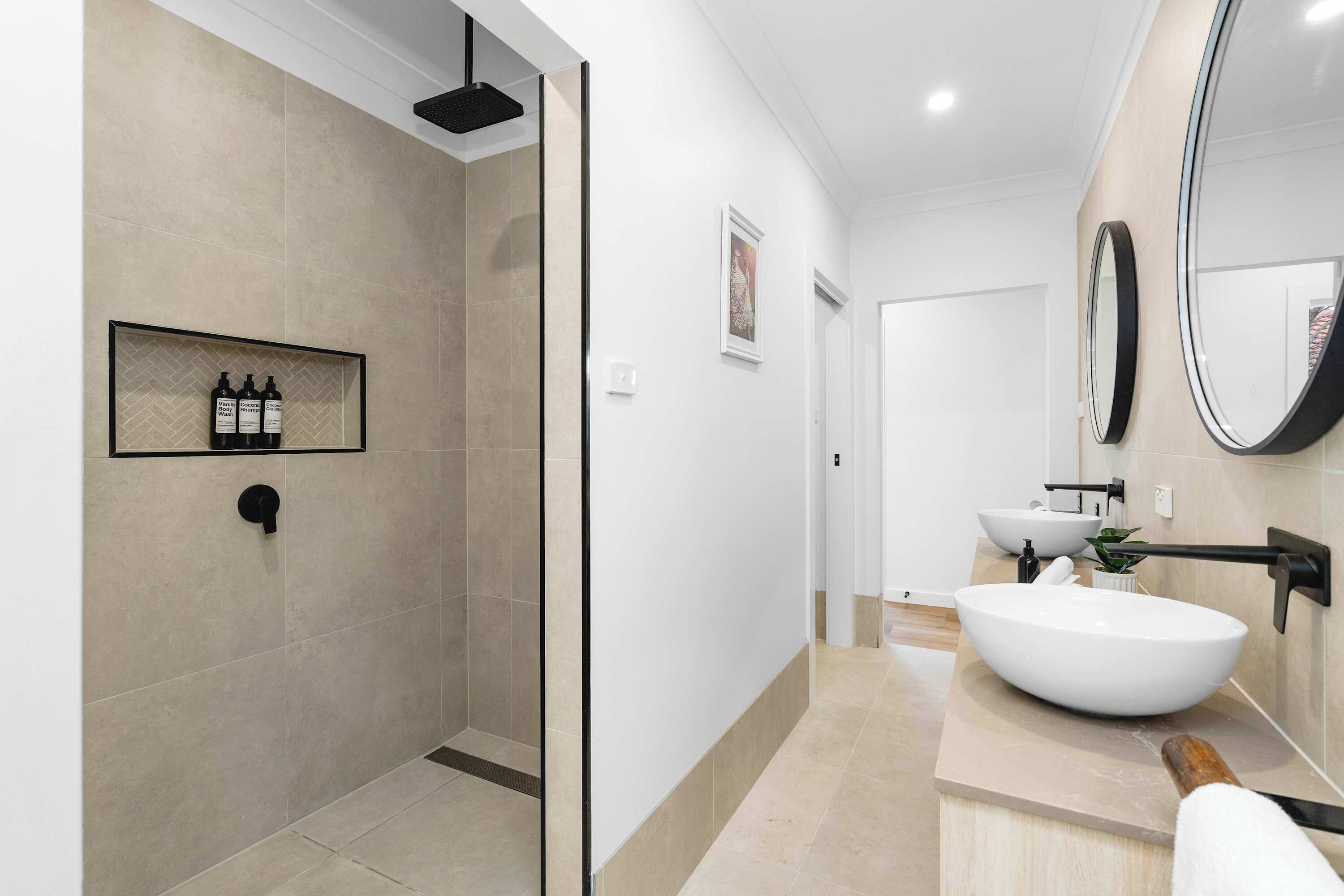 Une salle de bain moderne avec une douche à parois de verre, un grand lavabo blanc et un miroir.