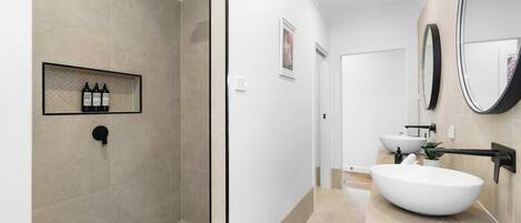 Une salle de bain moderne avec une douche à parois de verre, un grand lavabo blanc et un miroir.