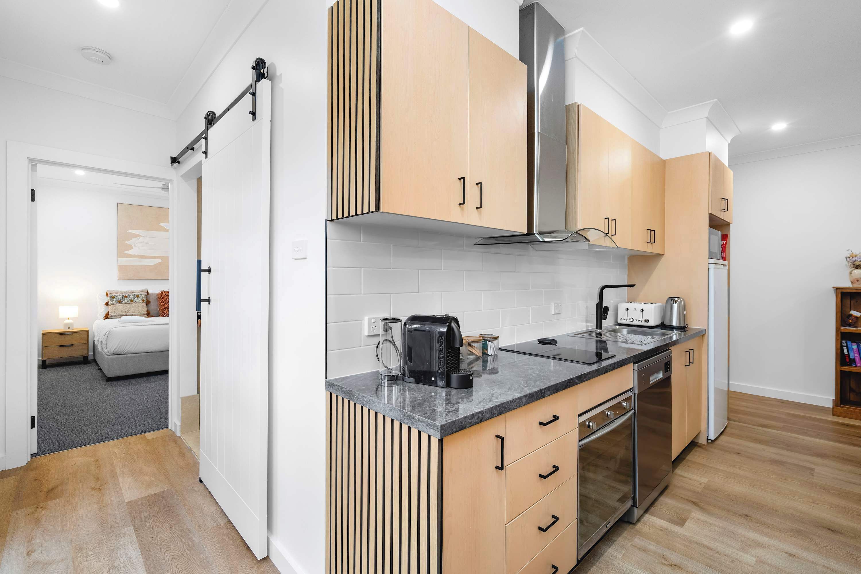 Una cocina moderna con armarios de madera, extractor de acero inoxidable y horno empotrado.