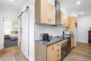 A modern kitchen with wooden cabinets, a stainless steel range hood, and a built-in oven. - Pirouette Place - Private Retreat, Heart of Wagga (Wagga Wagga)