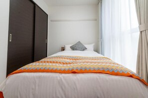 Una habitación de hotel con cama, armario y ventana con cortinas.