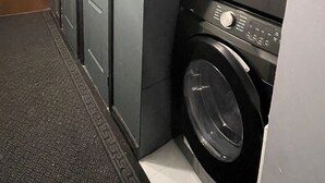 A laundry room with a washing machine, a door, and a patterned wall.
