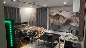 Une chambre moderne avec un lit, un canapé, une table basse et une grande fresque murale.