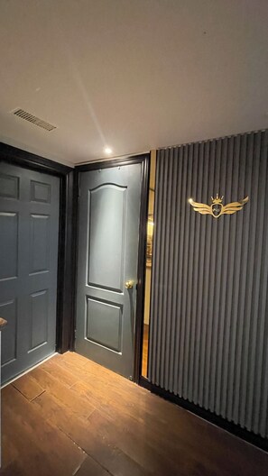 Una stanza con una porta grigio scuro, un termosifone e una parete con uno stemma decorativo.