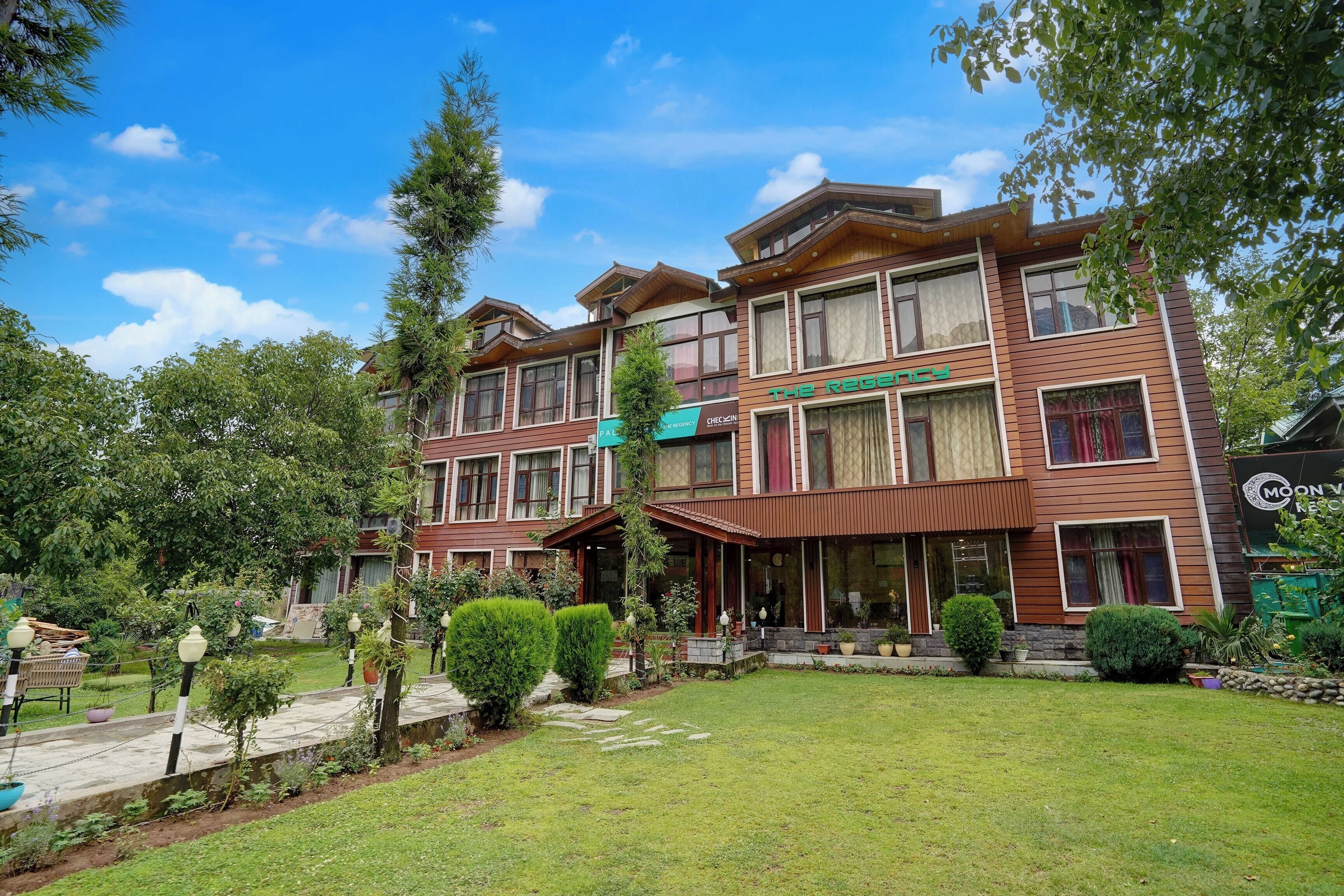 A multi-story hotel with a well-maintained lawn and garden.