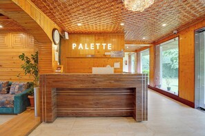 Uma área de recepção com um balcão de madeira, um relógio e uma placa com a inscrição 'PALETTE'.