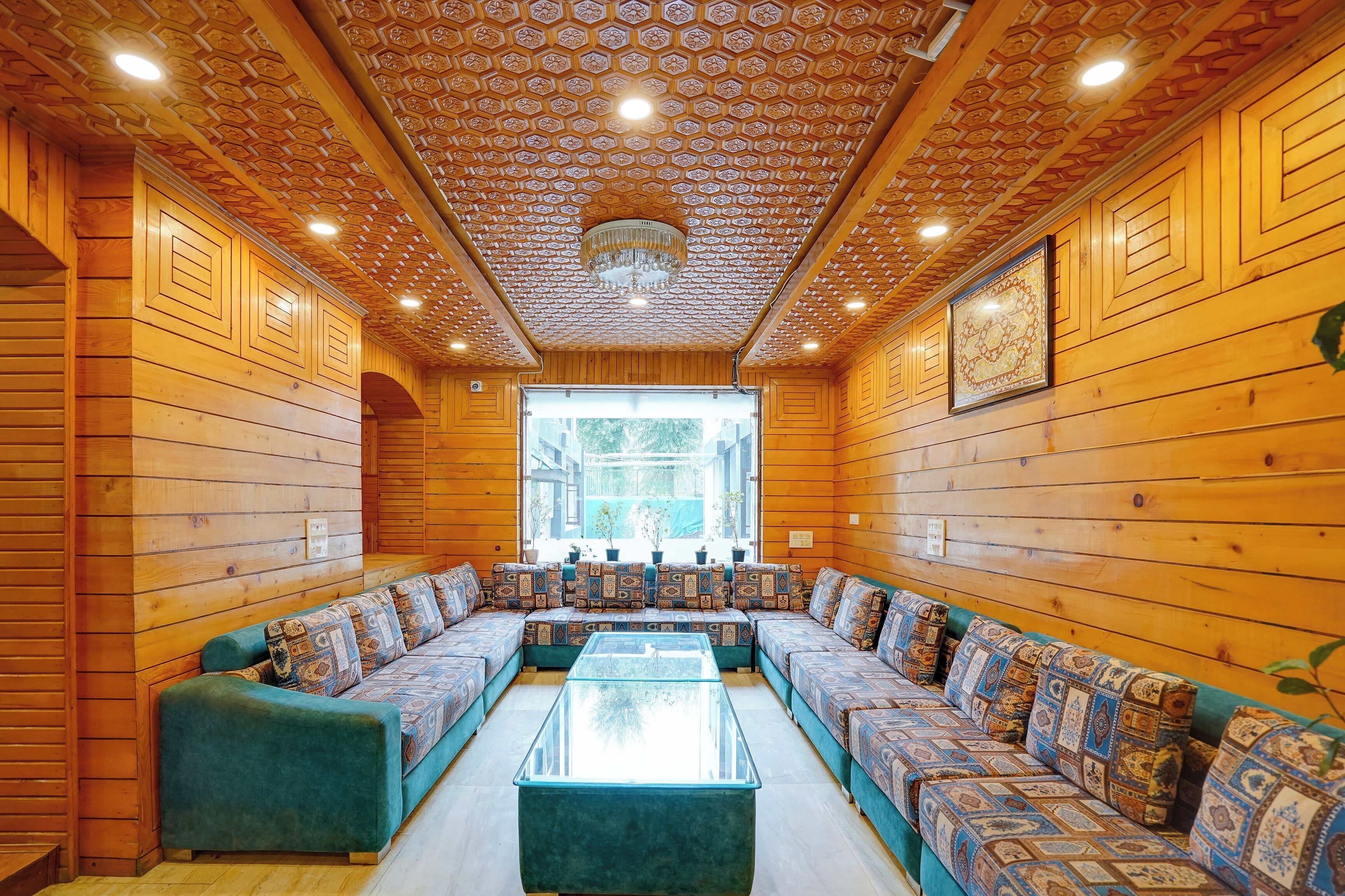 A log cabin interior with a large central seating area, wooden walls, and a patterned ceiling.