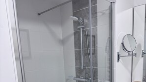 A modern bathroom with a glass-enclosed shower, a wooden vanity, and a mirror. - Stella Maris, the luxury apartment (Saint-Pierre-d'Oléron)