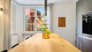 Et køkken med et træbord, et vindue med udsigt til grønne områder, og et moderne køleskab.