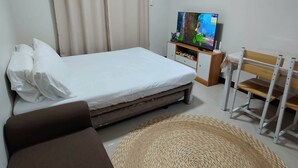 A bedroom with a bed, a TV, a desk, and a chair.