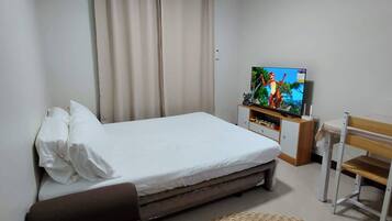 Ein Schlafzimmer mit Bett, Fernseher, Schreibtisch und Stuhl.