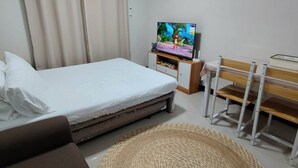 A bedroom with a bed, a television, a desk, and a chair.