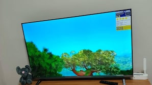 Ein Fernsehgerät auf einem Holz-TV-Schrank mit Fernbedienung, einem Kuscheltier und einer Spielkonsole.