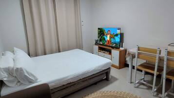 Ein Hotelzimmer mit Bett, Fernseher, Schreibtisch und Stuhl.
