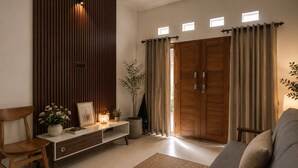 A modern living room with a wooden cabinet, a sofa, a chair, and a potted plant. - Dangin Tukad Villa (Badung)