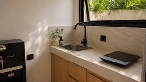 A kitchen with a countertop, a sink, a water dispenser, and a scale. - Dangin Tukad Villa (Badung)