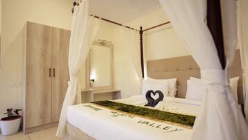 A bedroom with a canopy bed, a wooden wardrobe, a bedside table, and a potted plant.