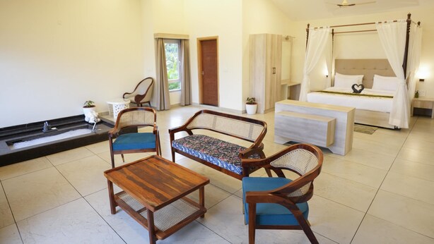 Een ruime kamer met een groot bed, een zithoek met stoelen en een tafel, en een klein balkon met een fontein.