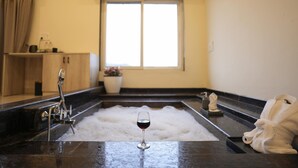 A bathroom with a bathtub, a glass of red wine, a towel, and a window. - The Divine Valley By Devandhari (Sakleshpur)