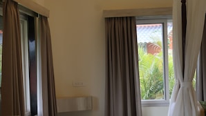 Een kamer met plafondventilator, raam met gordijnen, ingebouwde wastafel en betegelde vloer.