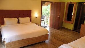 A hotel room with a large bed, a wooden headboard, a nightstand, a wall-mounted lamp, and a view of the outdoors.