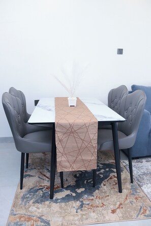 A dining table with a geometric patterned table runner, two upholstered chairs, and a vase with white flowers. - Modern cozy Retreat (Nairobi)