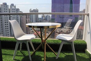 A balcony with a round table and two white chairs, overlooking a cityscape with high-rise buildings. - Modern cozy Retreat (Nairobi)