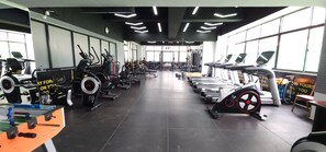 A gym with various exercise equipment, including treadmills and weight machines, arranged in rows. - Modern cozy Retreat (Nairobi)