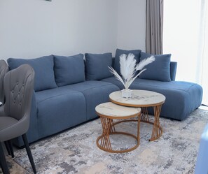 A modern living room with a grey sofa, two round tables with a marble top, and a decorative plant. - Modern cozy Retreat (Nairobi)