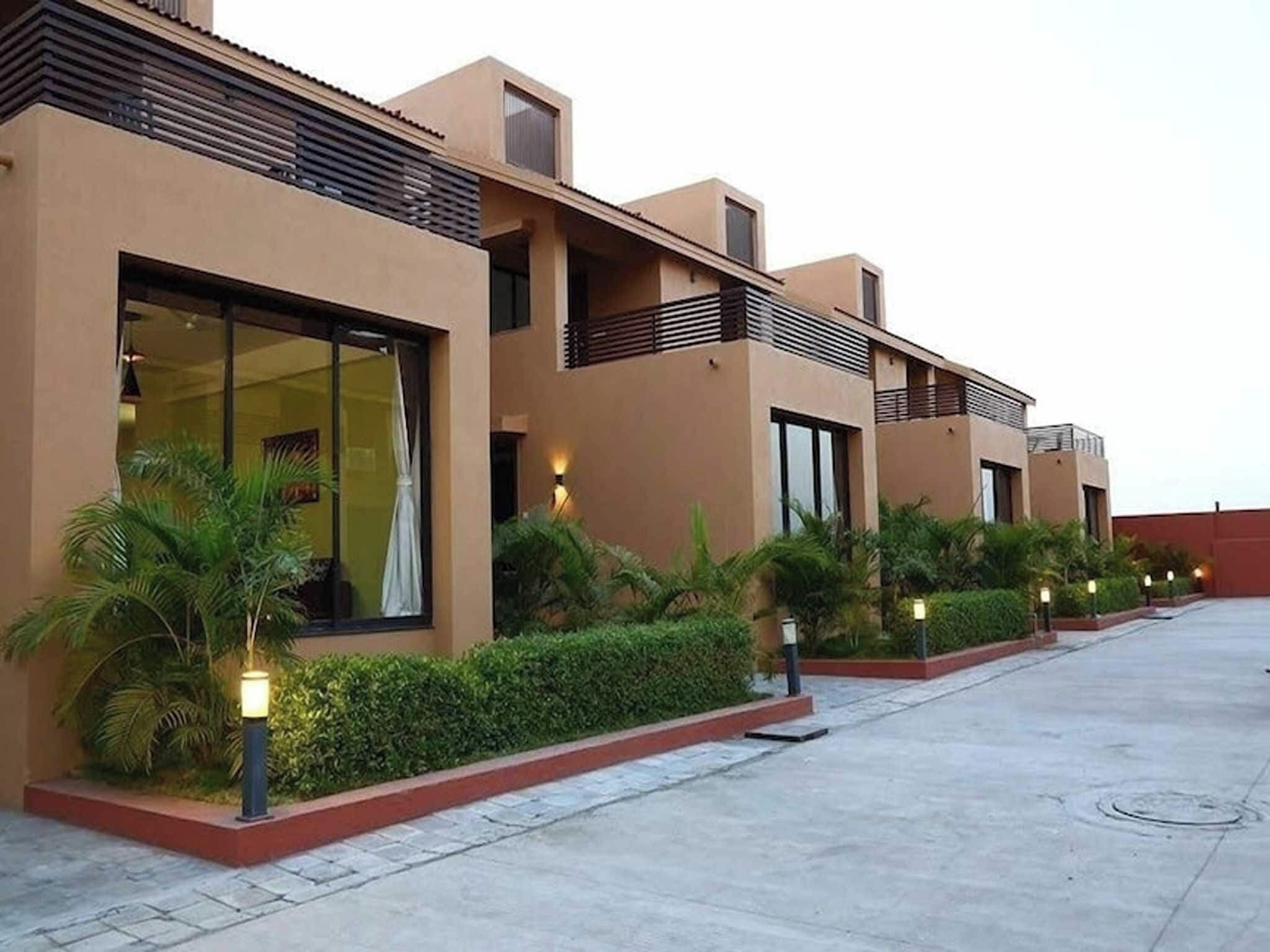 A modern building with large windows, a flat roof, and a paved courtyard.