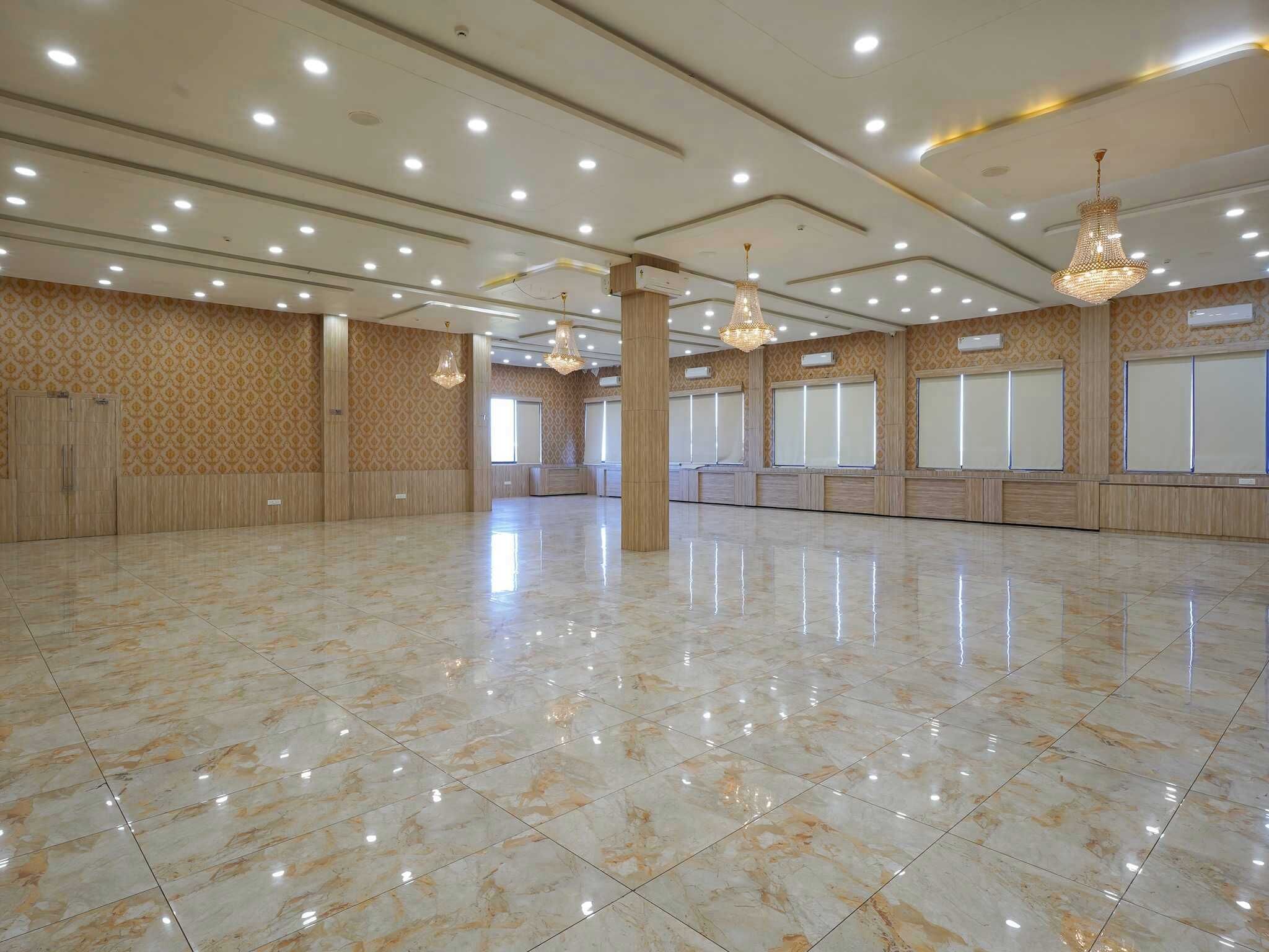 Un amplio salón con suelo de mármol pulido, papel tapiz estampado y múltiples luces en el techo.