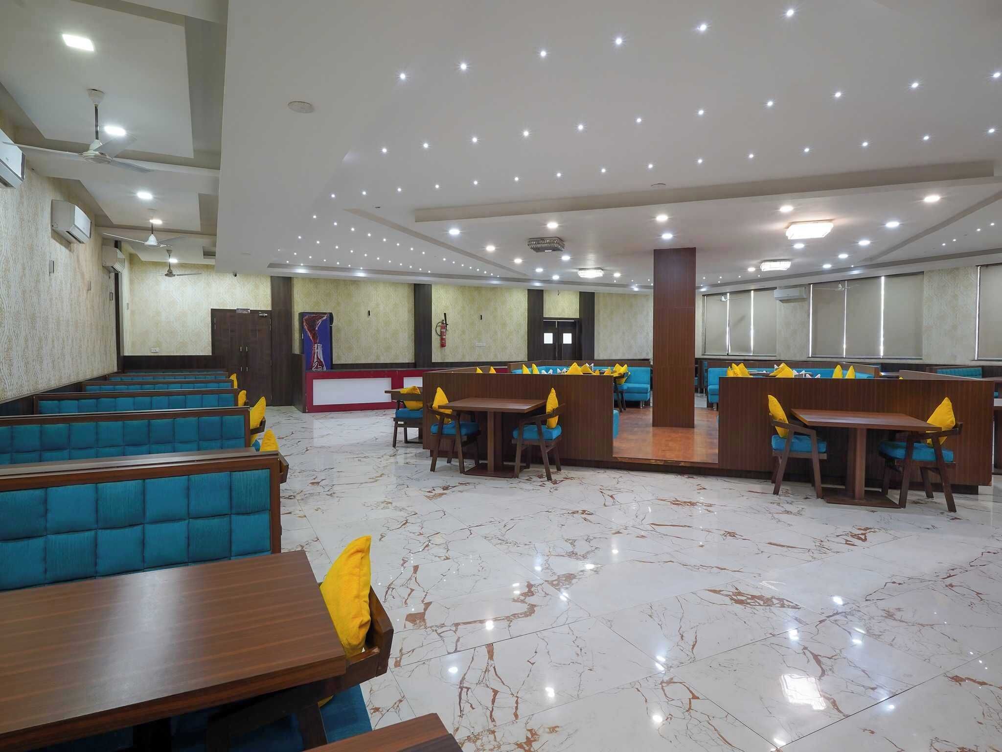 A spacious restaurant with high ceilings, recessed lighting, and a marble floor.