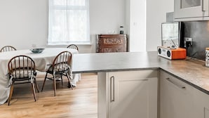 Uma cozinha moderna com um rádio embutido, um espaço de refeições com mesa e cadeiras, e uma janela com cortinas estampadas.