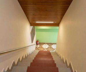 Una escalera con techo de madera, un extintor y un suelo con diseño.